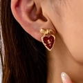 Elegant gold bow heart earrings with red enamel and rose relief on a female model - Burgundy