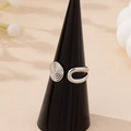 Minimalist silver spiral open ring on a black display stand with elegant beige background - Silver White