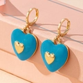 Gros plan détaillé des boucles d'oreilles cœur en émail bleu ciel et métal doré - Bleu