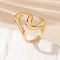 Macro detail of a minimalist gold irregular wave ring on a textured stone display - Gold Yellow