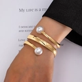 Bracciale rigido a spirale dorata con due grandi perle indossato sul polso - Giallo Oro