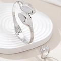 Detailopname van minimalistische zilveren ring en armband set op een witte getextureerde voet - Zilver Witte Set