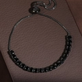 Detailed macro view of an adjustable black crystal box chain bracelet on a leather box - Black