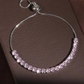 Adjustable silver tennis bracelet with pink cubic zirconia on dark leather background - Pink