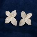 Goldene Blumenohrstecker mit glitzernden Zirkonia auf einem dunkelblauen Samtboden - Vierblättriges Blumen-Stil (Goldton) / Gold