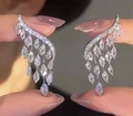 Silver wing tassel earrings with white zircon stones held between fingers - EP598 Platinum Plated Earrings