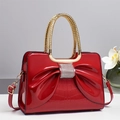 Elegant red patent leather handbag featuring a large rhinestone bow and crocodile texture - Red
