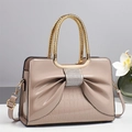 Detail showing nude patent leather handbag with rhinestone bow and croc texture - Khaki