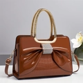 Close-up of a caramel patent leather bag with a crystal bow and faux crocodile texture - Brown