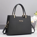 Elegante bolso negro con textura tejida, logo dorado y correa en un entorno moderno - Negro