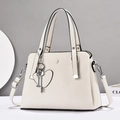 Detailed view of off-white lychee texture leather handbag with heart and key charms - White