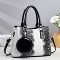 Close-up of white snake pattern handbag with round coin purse charm and black handles - White