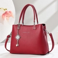 Detalle de bolso rojo oscuro con textura de lichi, colgante de perla y cadena de metal - Granate