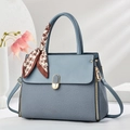 Elegant fog blue shoulder bag with scarf handle on a minimalist geometric background - Blue