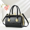 Detail of black crocodile texture handbag with gold metal frame and pearl clasp closure - Black