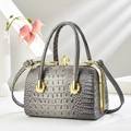 Detailed view of grey crocodile pattern handbag with gold hardware and pearl clasp closure - Gray