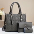 Close-up of grey diamond-quilted three-piece handbag set with gold hardware on white surface - Gray