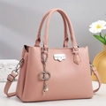 Detailed macro view of litchi textured leather shoulder bag with metallic buckle accent - Pink