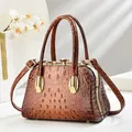 Detailed view of brown crocodile texture and gold hardware on evening handbag - Earthy Yellow
