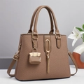Detail der braunen Web-Handtasche mit goldenen Beschlägen und Fransen-Anhänger - Braun