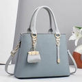 Dettaglio borsa tote a righe azzurra con finiture dorate e ciondolo mini borsa - Blu
