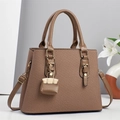Brown striped handbag with leather handles and gold charm in a modern minimalist setting - Brown