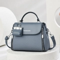 Close-up of navy blue structured handbag with woven texture and mini bag charm - Blue