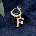 Goldener Creolen-Ohrring mit F-Buchstaben-Anhänger und Zirkon-Besatz auf blauem Samt - Gold F