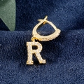 Goldener Ohrring mit Buchstabe R Anhänger und Zirkonia auf dunkelblauem Stoff - Buchstabe R Gold