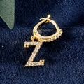 Goldener Creolen-Ohrring mit Z-Anhänger und Zirkonia-Steinen auf blauem Samt - Buchstabe Z Gold