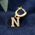 Goldener Ohrring-Anhänger Buchstabe N mit Zirkonia-Besatz auf dunkelblauem Grund - Buchstabe N Gold