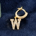 Einzelner Goldohrring mit Zirkonia-besetztem W-Anhänger auf blauem Samt-Hintergrund - Buchstabe W Gold