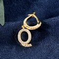Vergoldeter Buchstabe Q Ohrring mit Zirkonia-Besatz auf tiefblauem Samthintergrund - Buchstabe Q Gold