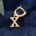 Goldene Creolen mit Buchstaben X und Zirkonia-Besatz auf dunkelblauem Samtgrund - Buchstabe X Gold
