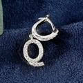 Silberner Q-Buchstaben-Ohrring mit Zirkonia-Besatz auf dunkelblauem Hintergrund - Buchstabe Q Platin