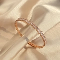 Detailed macro view of rose gold bangle featuring pavé-set rectangular cubic zirconia stones - Rose Gold