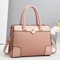 Close-up of pink pleated leather handbag with gold metal clasp and adjustable strap - Pink