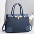 Detail of blue paneled tote bag featuring pleated texture and gold logo pendant - Blue