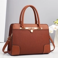 Detail of caramel brown tote bag with striped texture, gold padlock, and dual handles - Earthy Yellow