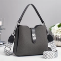 Close-up of a dark grey bucket bag featuring a textured fabric and woven shoulder strap - Gray