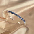 Silver open bangle with rectangular blue zircons on champagne silk backdrop - Sapphire Blue