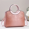 Detail of pink crocodile embossed tote bag with gold rivets and smooth circular handles - Pink