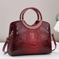 Detail of burgundy crocodile-embossed tote bag with shiny finish and gold rivets - Wine Red
