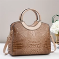 Close-up of brown crocodile pattern handbag with glossy finish and golden metal rivets - Khaki
