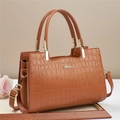 Detail of brown faux-crocodile texture tote with gold hardware and elegant top handles - Brown