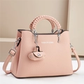 Detail of light pink lychee texture handbag with woven handle and fashion bag charm - Pink