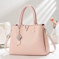Detail shot of the pink embossed leather bag featuring a metal V-logo and chic charm - Pink