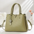 Détail du sac en cuir vert foncé avec texture tressée, boucle dorée en V et pompon déco - Vert