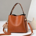 Brown leather bucket bag with top handle and plush cloud charm on adjustable shoulder strap - Brown