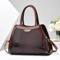 Close-up of chocolate brown faux lizard texture and gold metal accents on bag - Coffee